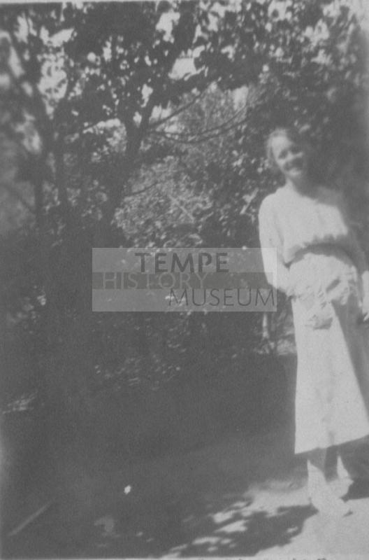 Velma in white dress near tree