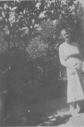 Velma in white dress near tree
