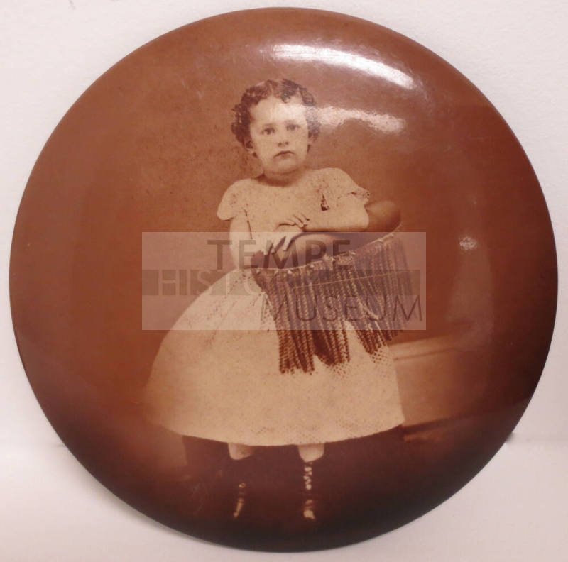 Portrait of young girl mounted on oval metal button