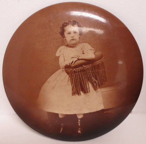 Portrait of young girl mounted on oval metal button