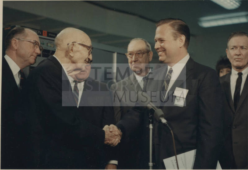 Carl shakes hand with man standing next to microphone.
