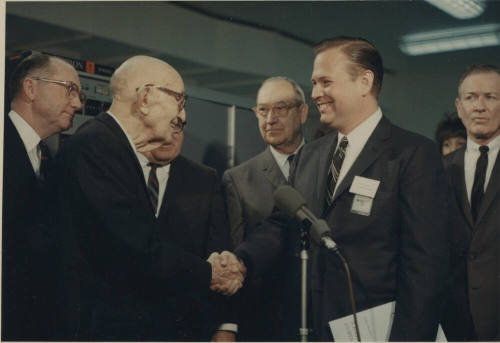 Carl shakes hand with man standing next to microphone.
