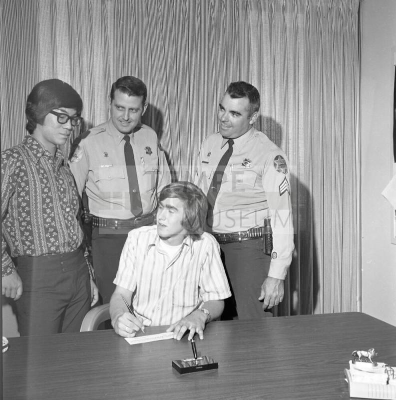 Two Police Officers and Teenage Boy at paper signing