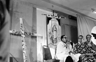 Cross, Virgin Mary, and Priests at Chavez's Fast Breaking Mass
