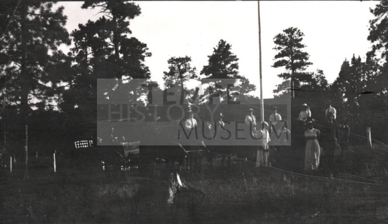 unknown people posing in front of pine trees