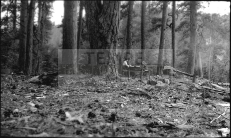Ruby and Dorothy Woolf sitting at table in campsite in forest
