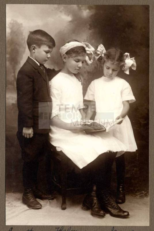 Photo of Everett, Thelma, and Irene Cummins reading a book