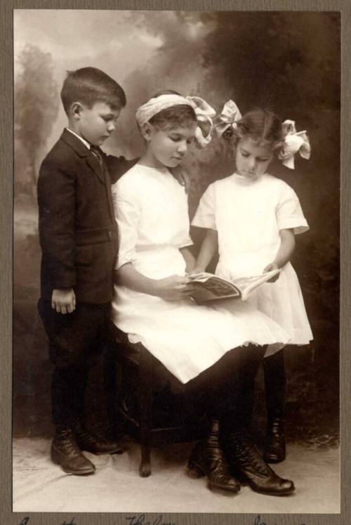 Photo of Everett, Thelma, and Irene Cummins reading a book