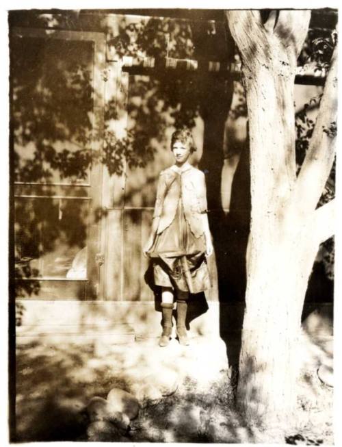 Picture of Ruby Laird Leaning on a Building under a  tree