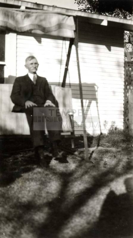 A Raymond Man sitting on a swing outside of a house