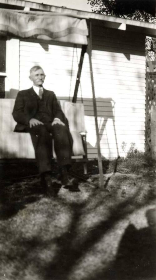 A Raymond Man sitting on a swing outside of a house