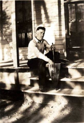Frank Raymond Sitting on Front Porch with an Umbrella