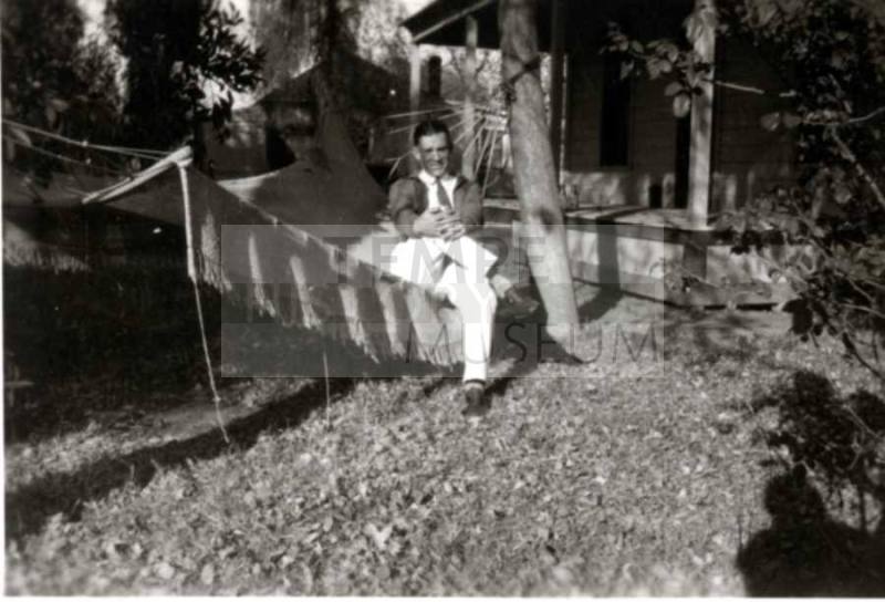 Frank Raymond sitting on hammock under trees
