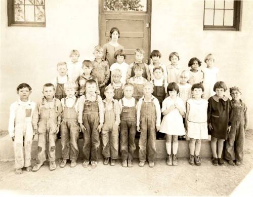 Minnie Laird and First Grade Stand in Front of Building