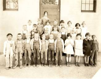 Minnie Laird and First Grade Stand in Front of Building