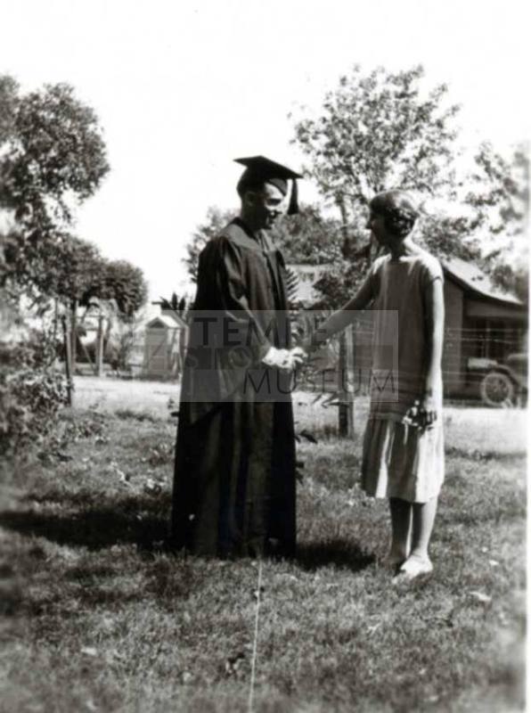 Frank Raymond in Cap and Gown Shaking Minnie's Hand