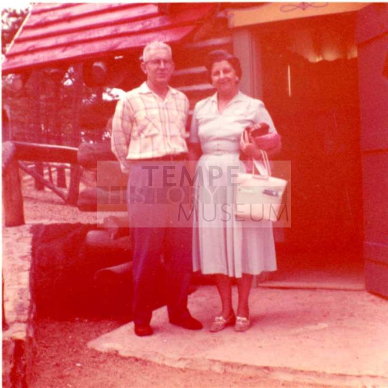 Frank and Minnie Raymond Stand in front of a Building