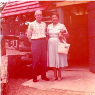 Frank and Minnie Raymond Stand in front of a Building