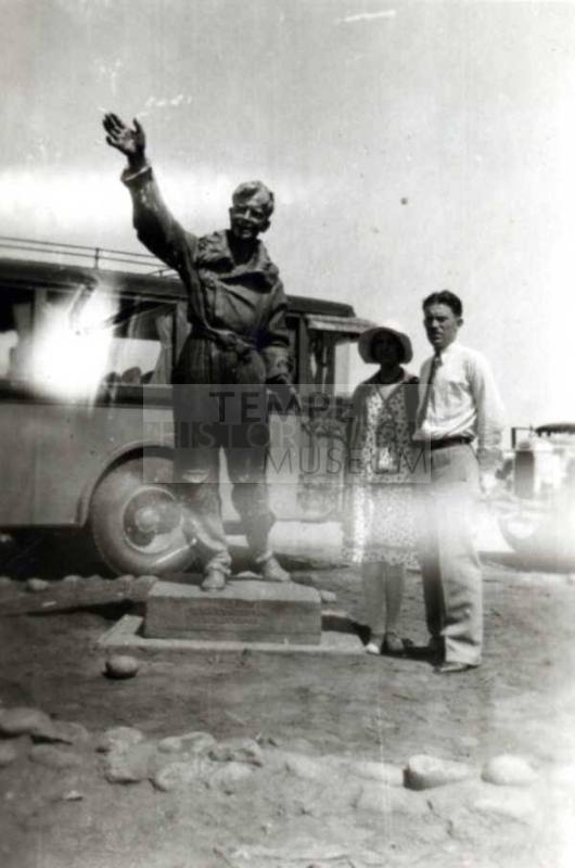 Frank and Minnie Raymond Stand Behind a Statue