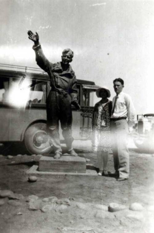 Frank and Minnie Raymond Stand Behind a Statue