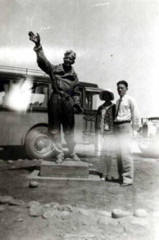 Frank and Minnie Raymond Stand Behind a Statue