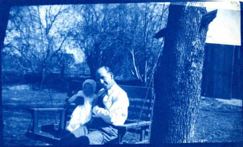 Bill Laird Holds Child on a Bench