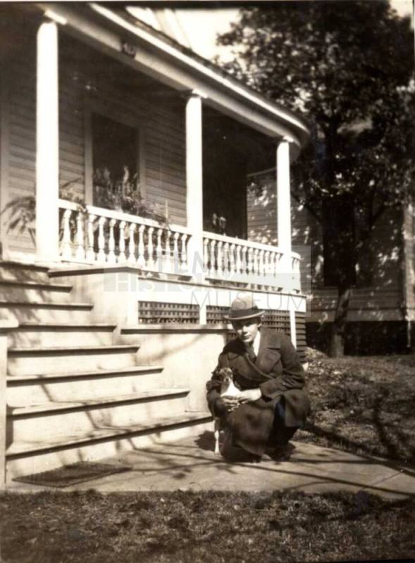 Man Kneeling with a Dog Near a Front Porch