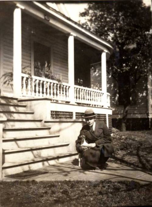 Man Kneeling with a Dog Near a Front Porch