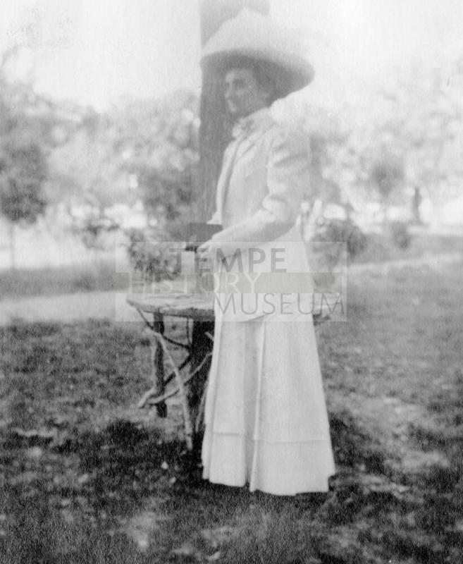 Woman standing by tree table in yard near Petersen House