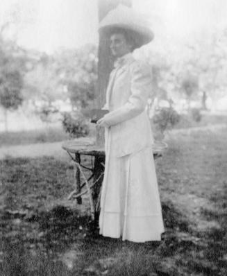 Woman standing by tree table in yard near Petersen House