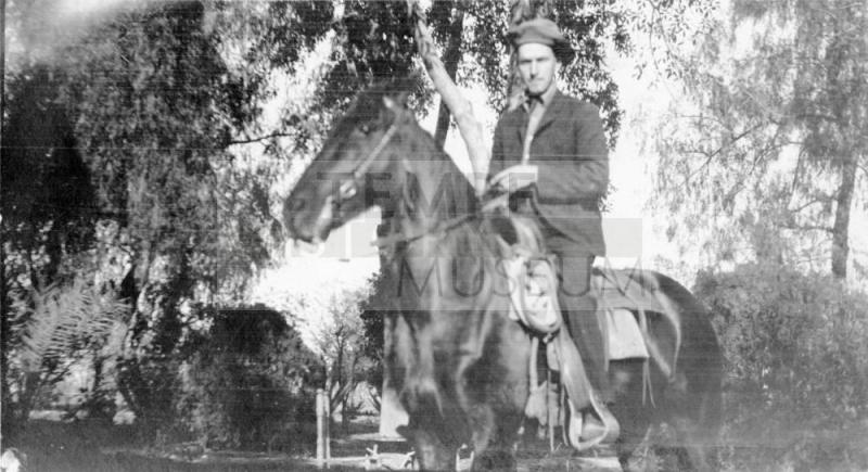 D.C.Stanion on a horse beneath some trees.
