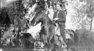 D.C.Stanion on a horse beneath some trees.