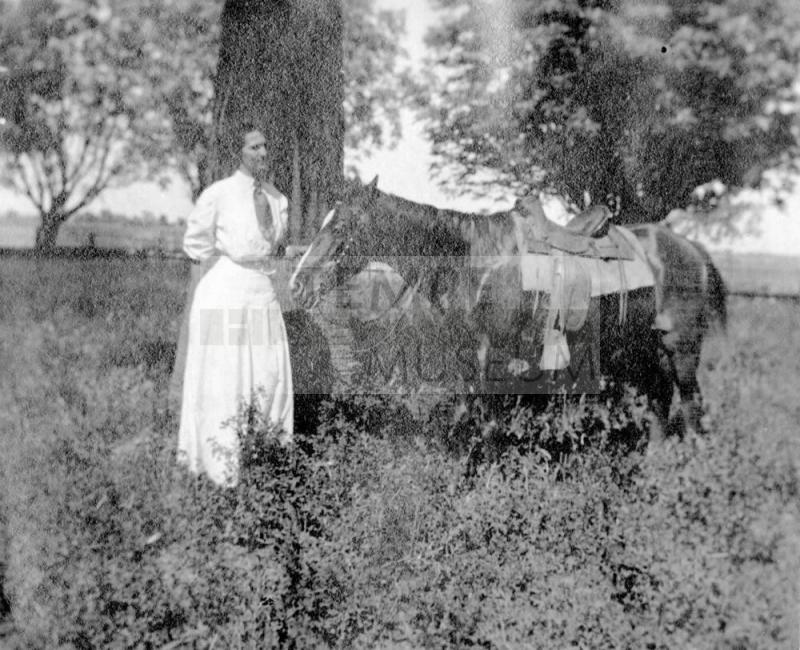 Woman standing by tree with horse