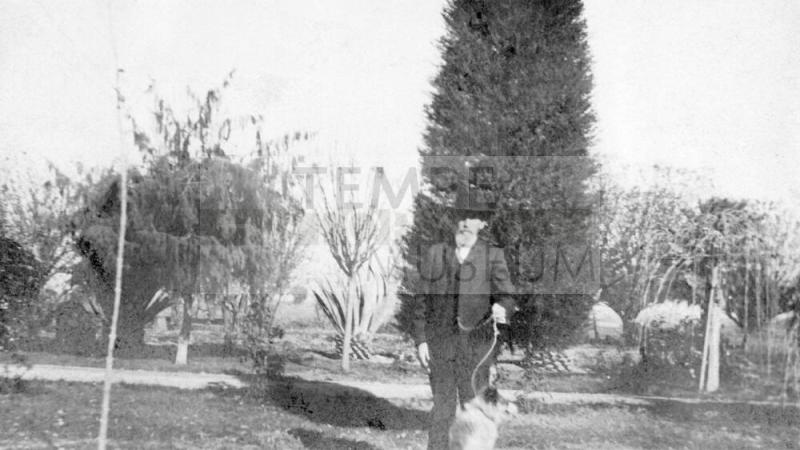 "Uncle Niels Petersen" and dog in Petersen House yard