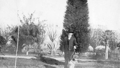 "Uncle Niels Petersen" and dog in Petersen House yard