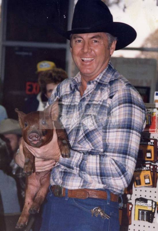 Photograph - Man in Western Attire holding a Pig