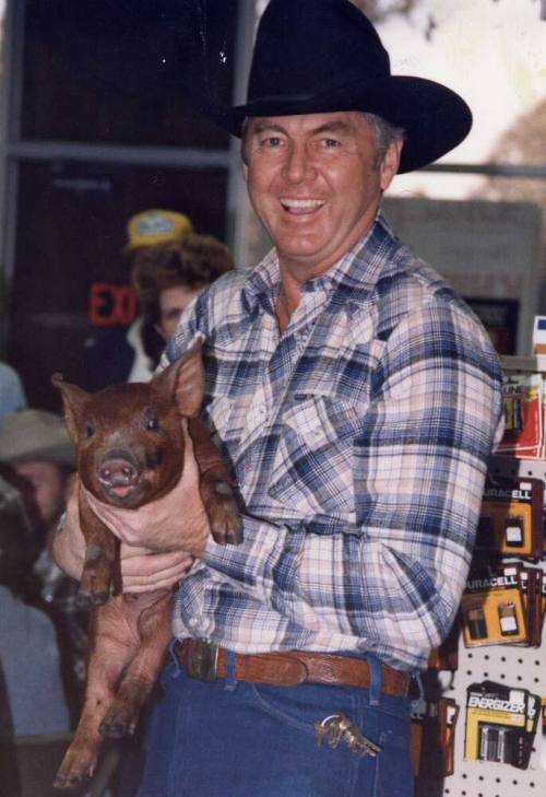 Photograph - Man in Western Attire holding a Pig