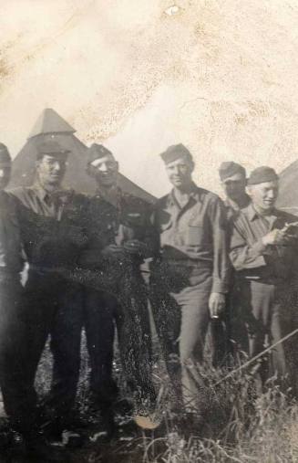 Photograph of six military personnel at a campsite