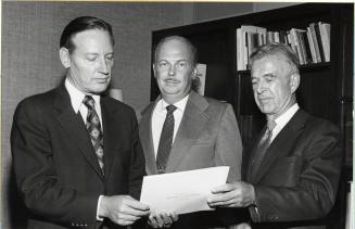 President Schwada and Two Men View Proclamation