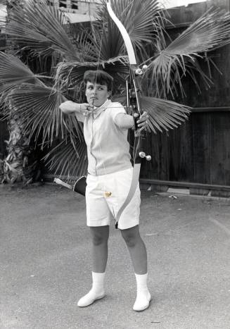 Judy Severance poses with a drawn bow