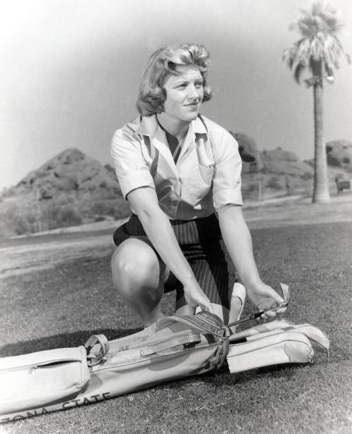 This black and white photo shows JoAnne Gunderson Carner removing a club from her golf bag.