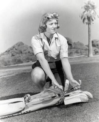 This black and white photo shows JoAnne Gunderson Carner removing a club from her golf bag.