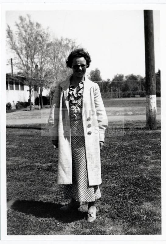Woman in long coat outside building on campus