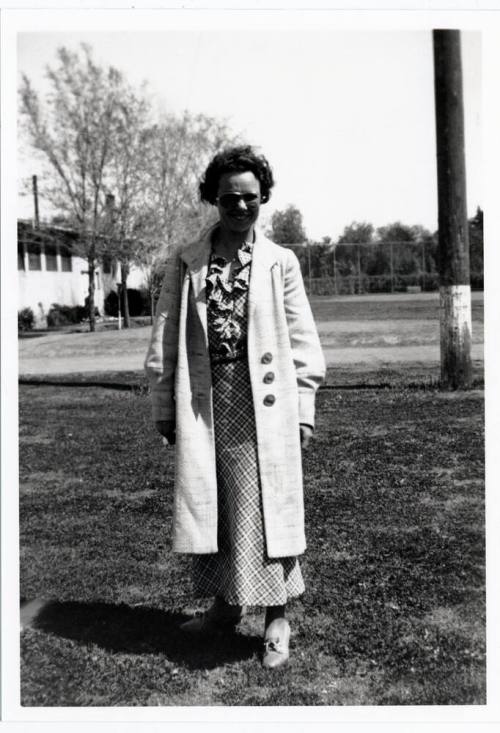 Woman in long coat outside building on campus