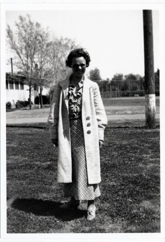 Woman in long coat outside building on campus
