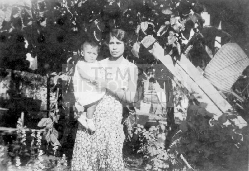 Irene Elias-Rodriguez holding a baby standing in the Elias Rodriguez House garden