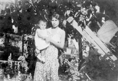 Irene Elias-Rodriguez holding a baby standing in the Elias Rodriguez House garden
