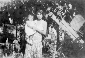 Irene Elias-Rodriguez holding a baby standing in the Elias Rodriguez House garden