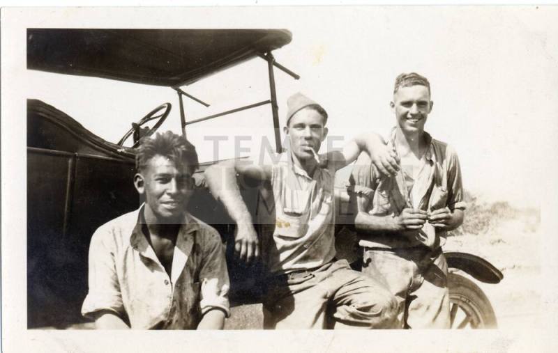 Three prisoners sit on a car