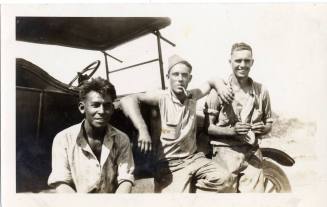 Three prisoners sit on a car